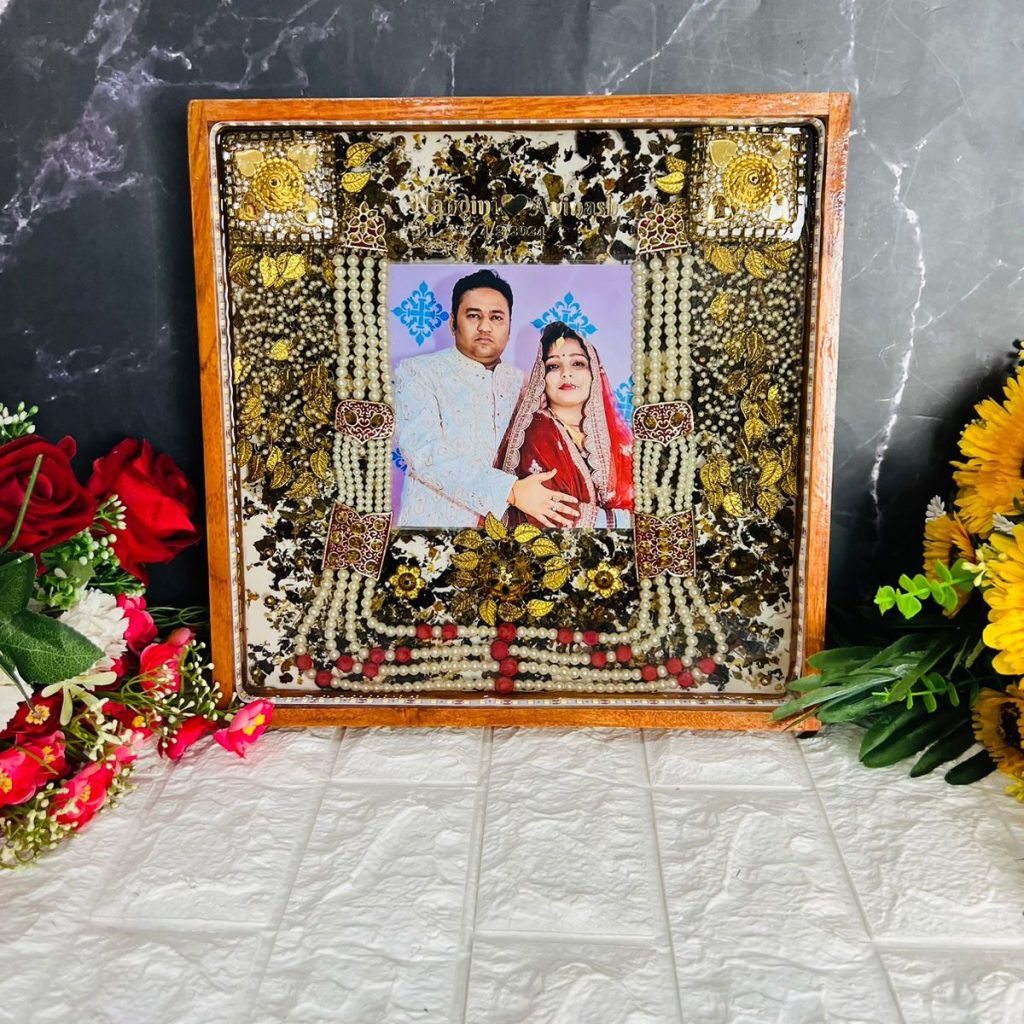 Square teakwood frame with preserved wedding varmala, photo, groom’s mala, kaleerein, and LED light